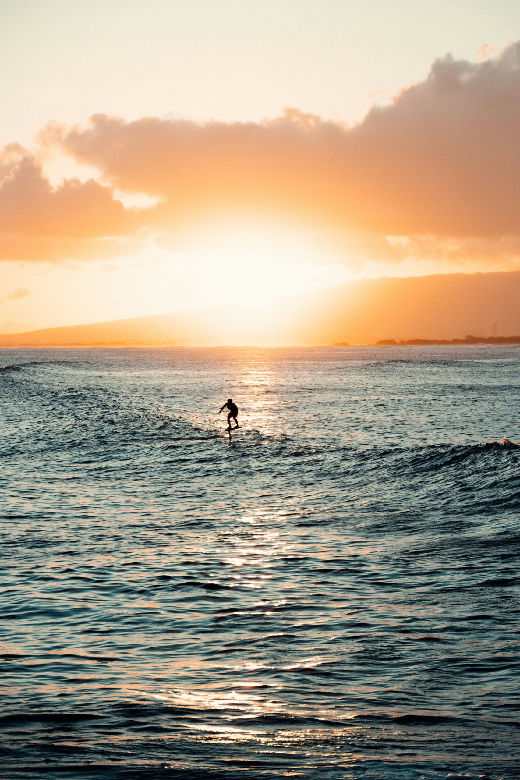 Surfer riding a wave at golden hour